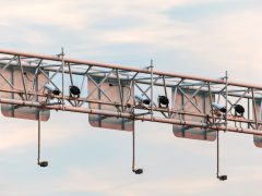 Een rij flitsers gemonteerd op een portaal boven het hoofd tegen een bewolkte hemel.