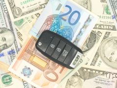 De sleutelafstandsbediening van een nieuwe auto geplaatst op verschillende internationale bankbiljetten.