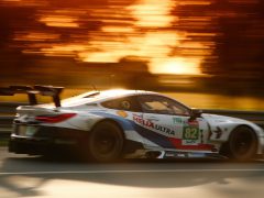 Een racewagen van Le Mans 2020 die bij zonsondergang over een circuit rijdt met bewegingsonscherpte op de achtergrond.