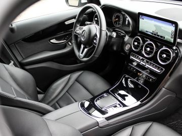 Binnenaanzicht van de Mercedes-Benz GLC met het stuur, het dashboard, de middenconsole en de lederen stoelen.