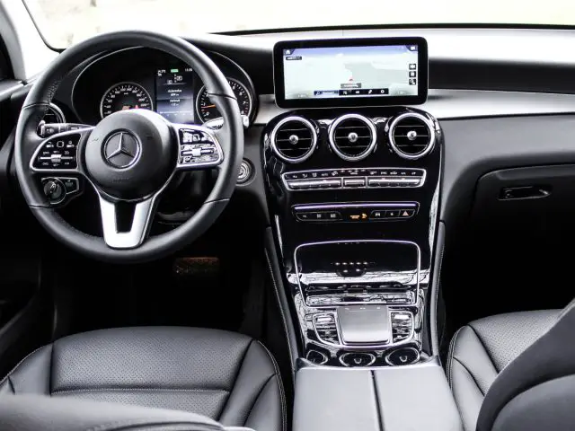 Binnenaanzicht van een Mercedes-Benz GLC met een stuur met gemonteerde bedieningselementen, een digitaal display en een middenconsole met bedieningselementen voor het klimaat- en infotainmentsysteem.