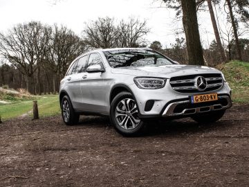 Zilveren Mercedes-Benz GLC SUV geparkeerd op een onverharde plek met bomen op de achtergrond.