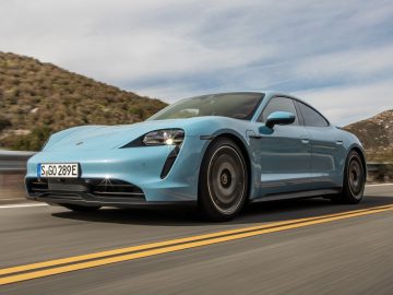 Een blauwe elektrische sportwagen, genaamd Auto van het Jaar 2020, rijdt op een snelweg.
