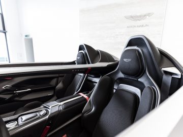 Binnenaanzicht van een moderne Aston Martin V12 Speedster, met de nadruk op de luxe lederen stoelen en middenconsole.