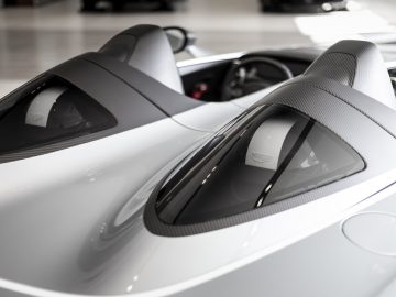 Close-up van de dubbele koolstofvezel motorkappen en cockpit van een Aston Martin V12 Speedster.