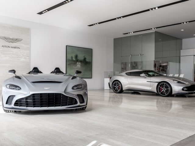 Twee luxe Aston Martin V12 Speedster-auto's tentoongesteld in een strakke showroom.
