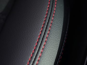 Close-up van het zwarte leer van de Ford Kuga met rode stiksels.