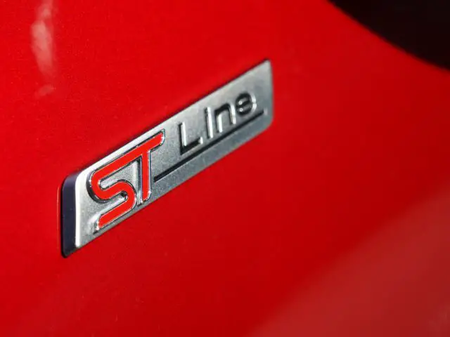 Close-up van een rode Ford Kuga met een "ST Line"-badge.