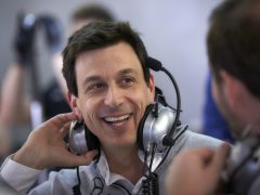 Man met hoofdtelefoon glimlachend tijdens een Wolff Aston Martin-gesprek.