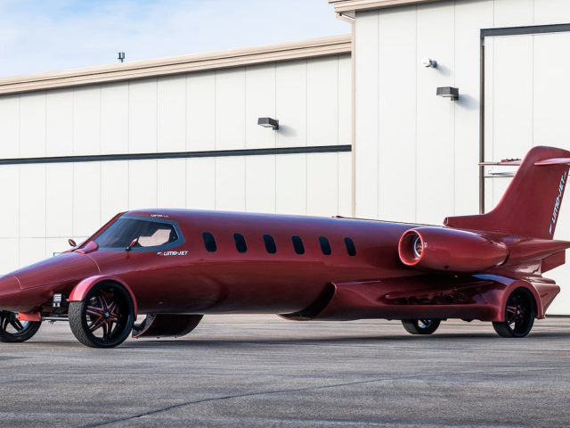 Een rode limousine geparkeerd voor een luchthavenhangar.
