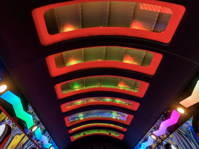 Levendig interieur van een moderne limousine met kleurrijke verlichting en een reeks bogen die een dynamisch gangperspectief creëren.