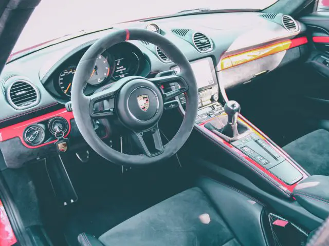 Binnenaanzicht van een Porsche 718 Cayman GT4-sportwagen met stuur, dashboard en middenconsole.