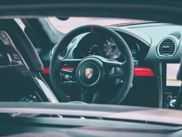 Binnenaanzicht van het stuur en het dashboard van een Porsche 718 Cayman GT4-voertuig.