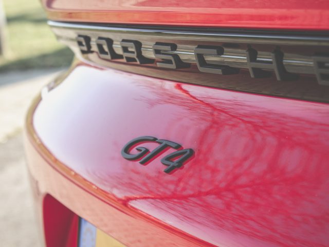 Close-up van het achterste embleem op een rode Porsche 718 Cayman GT4.