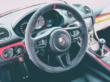 Binnenaanzicht van een Porsche 718 Cayman GT4-voertuig, gericht op het stuur en het dashboard.