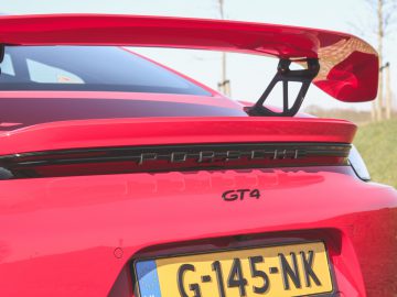 Achteraanzicht van een rode Porsche 718 Cayman GT4 met een prominente spoiler.