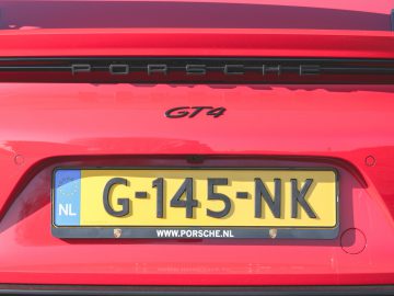 Rode Porsche 718 Cayman GT4 met Nederlands kenteken geparkeerd.