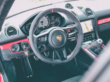 Binnenaanzicht van een Porsche 718 Cayman GT4 met het stuur en het dashboard.