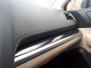 Binnenaanzicht van een Subaru Outback met een deel van het dashboard, een deur met bedieningselementen en een zijraam.