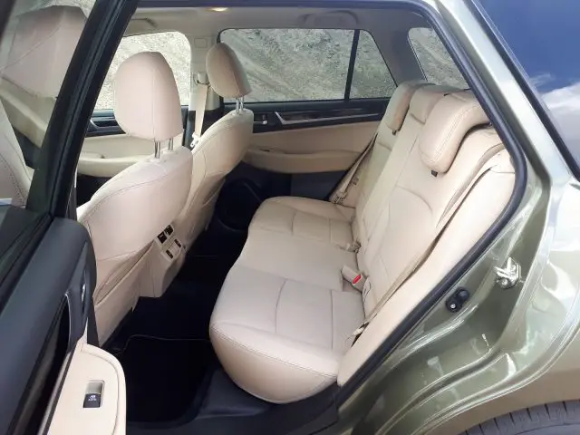 Een weergave van het interieur van een Subaru Outback met beige lederen achterstoelen met de voordeur aan de passagierszijde open.