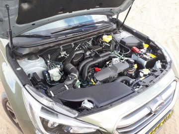 Een moderne Subaru Outback-motorruimte met de motorkap open, waardoor verschillende motoronderdelen en vloeistofreservoirs zichtbaar zijn.