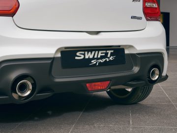 Close-up van de achterbumper en uitlaat van een witte Suzuki Swift Sport-auto.