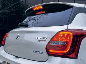 Een close-up van de achterkant van een Suzuki Swift Sport, met de nadruk op de achterlichten en het embleem.