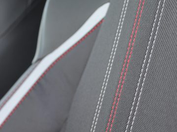 Close-up van een Toyota Corolla-autostoeltje met structuurstof en rode stiksels.