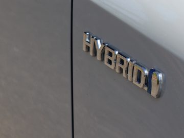 Close-up van een Toyota Corolla hybride voertuigembleem op de zijkant van een auto.