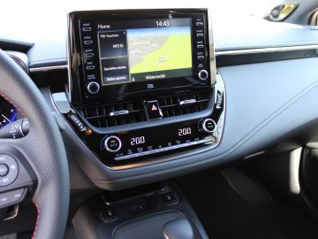 Binnenaanzicht van het dashboard van een moderne Toyota Corolla met een infotainmentsysteem met navigatiedisplay, klimaatregeling en stuurwiel.