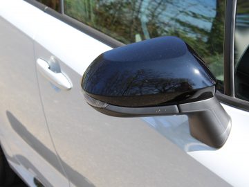 Close-up van de zijspiegel van een Toyota Corolla.