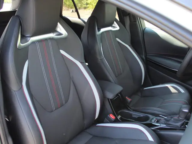 Binnenaanzicht van een Toyota Corolla met zwarte voorstoelen met rode stiksels.