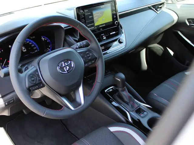 Interieur van een moderne Toyota Corolla met het stuur, het dashboard en het infotainmentsysteem.