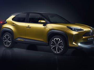 Moderne goudkleurige Toyota Yaris Cross op een donkere achtergrond.