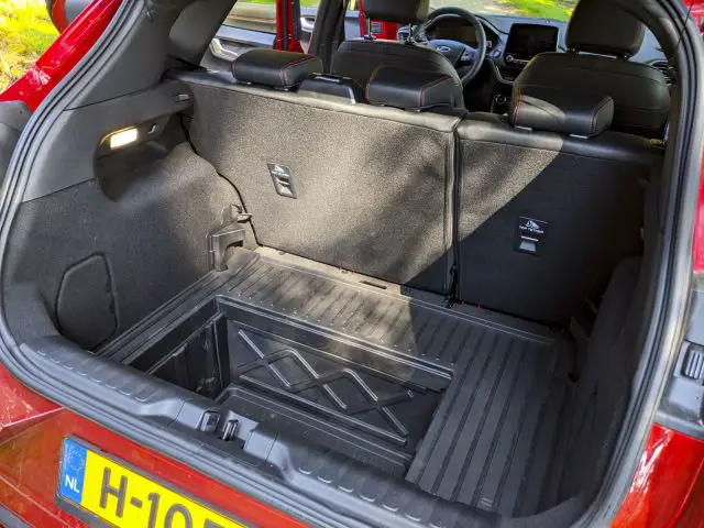 Open kofferbak van een Ford Puma met een ruime laadruimte met de achterbank gedeeltelijk neergeklapt en een opvouwbare krat erin.