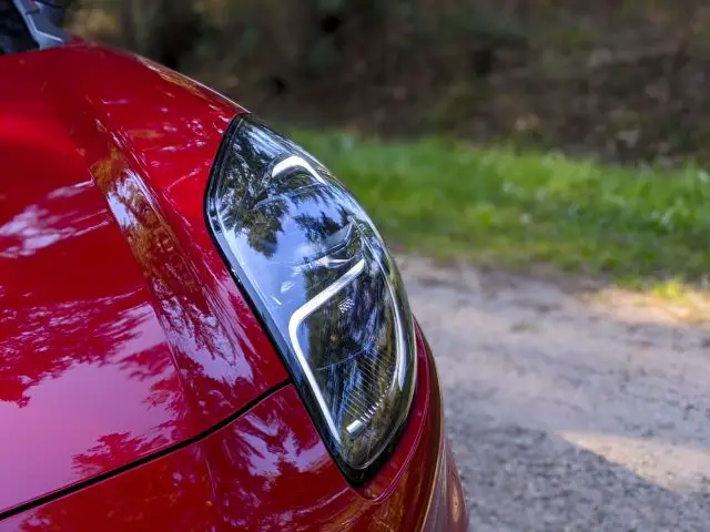 Close-up van het rode achterlicht van een Ford Puma met een wazige groene achtergrond.