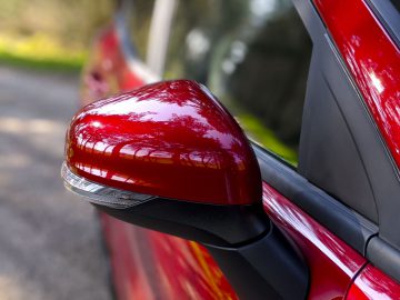 Rode Ford Puma autozijspiegel met een onscherpe achtergrond.