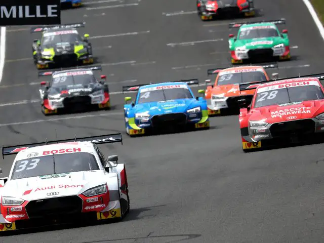 Audi DTM-toerwagens racen op een circuit tijdens een competitief autosportevenement.