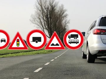 Een auto rijdt op een weg met verschillende verkeersborden digitaal op de voorgrond erop.