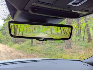 Uitzicht op een bospad, weerspiegeld in de achteruitkijkspiegel van een Range Rover.