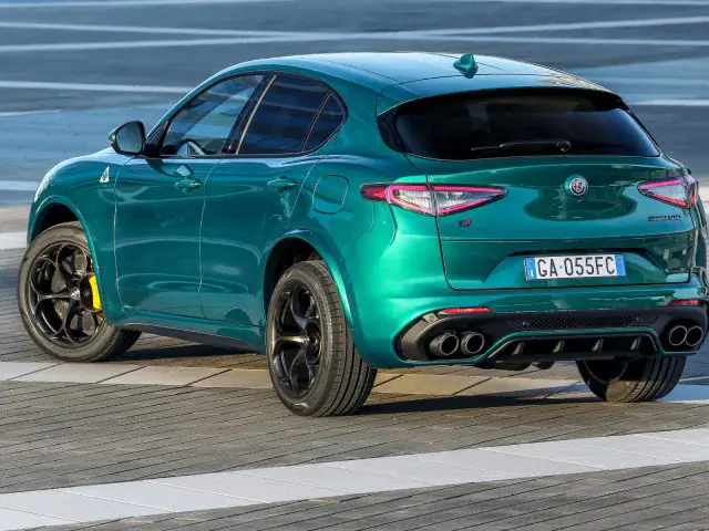 Blauwgroen Alfa Romeo Giulia Quadrifoglio geparkeerd op een verhard terrein.