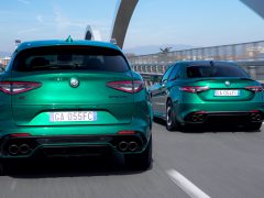 Twee groene Alfa Romeo Giulia Quadrifoglio-voertuigen rijden op een brug.