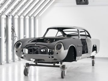 Een Aston Martin DB5 Goldfinger Continuation-chassis zonder motor of wielen in een werkplaatsomgeving.