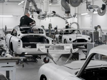 Autotechnici werken aan de carrosserie van een Aston Martin DB5 Goldfinger Voortzetting in een moderne autowerkplaats.