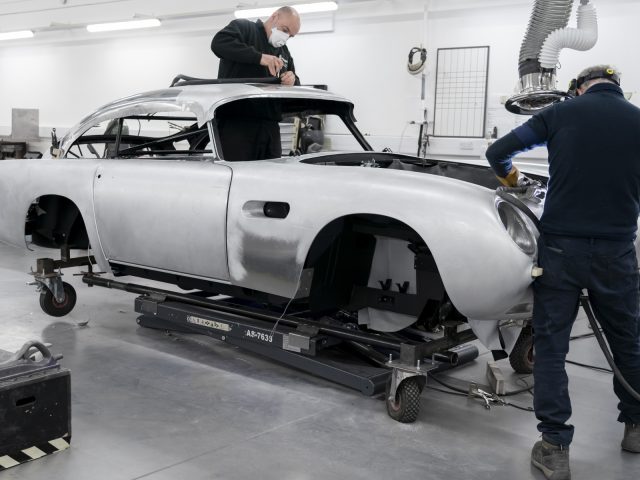 Twee monteurs bezig met de restauratie van een Aston Martin DB5 Goldfinger Vervolg in een werkplaats.