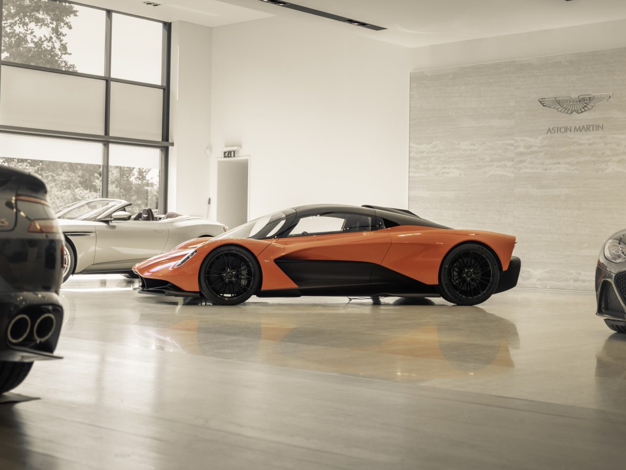 Een Aston Martin Valhalla tentoongesteld in een showroom met andere luxe voertuigen.