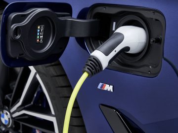 Oplaadkabel voor elektrische voertuigen aangesloten op de oplaadpoort van een blauwe BMW 5-serie auto.