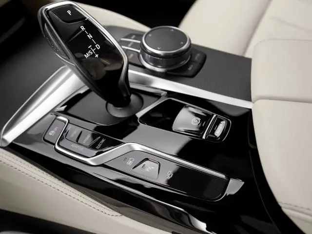 Close-up van de automatische versnellingspook en multimediabedieningsknoppen van een BMW 5 Serie op de middenconsole.