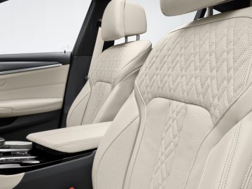 Luxe BMW 5 Serie interieur met beige lederen stoelen en modern dashboarddesign.