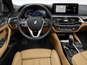 Binnenaanzicht van een BMW 5 Serie-voertuig met het stuur, het dashboard en de luxe lederen stoelen.